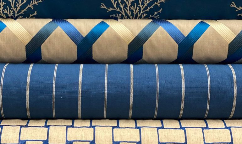 Stack of folded fabrics with blue and beige geometric and coral patterns.