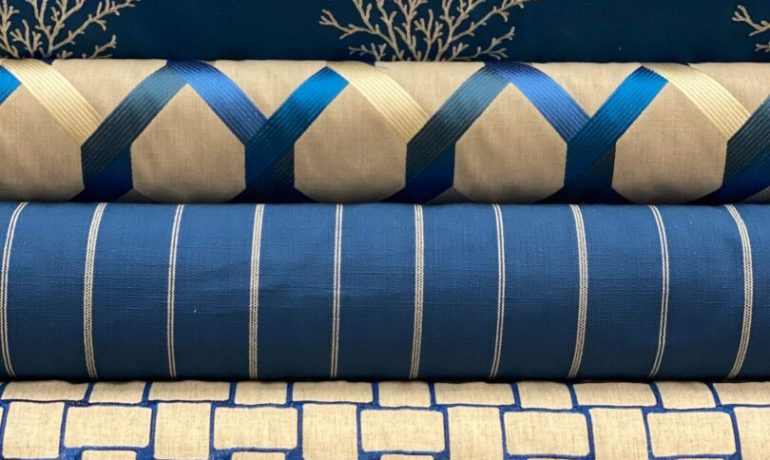 Stack of folded fabrics with blue and beige geometric and coral patterns.