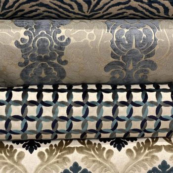 Three elegant fabric rolls with intricate patterns in soft colors.